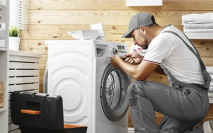 Engineer repairing a washing machine in a London home